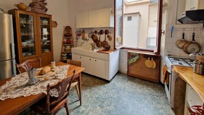 A kitchen with a wooden table, chairs, a refrigerator, a stove, and various kitchen utensils.