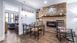 Una habitación con chimenea de piedra, una mesa de comedor con sillas, una cama litera y un armario de madera.