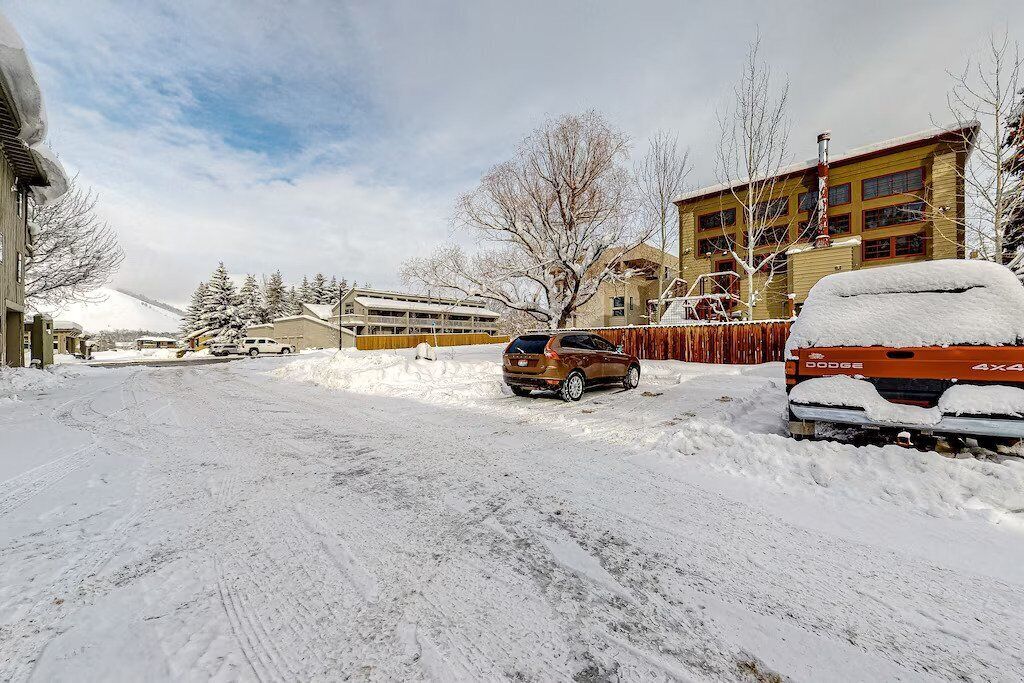 A snow-covered street with a building that has multiple windows and a chimney.