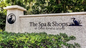 Señalización para "The Spa & Shops at Omni Amelia Island" con un logotipo de un ave y follaje.
