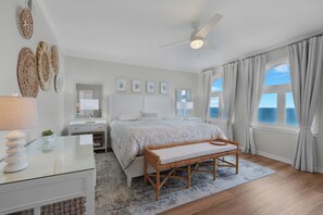 Ein Schlafzimmer mit Bett, Nachttischen, Schreibtisch, einer Bank und einem Deckenventilator.