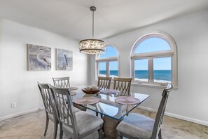 A dining area with a glass table, chairs, and artwork on the walls.