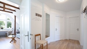 A spacious hallway with wooden flooring, white doors, and a dining area with a table and chairs.