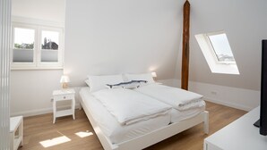A bedroom with a bed, bedside tables, a window, and a skylight.