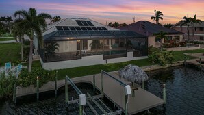 Una casa moderna con un invernadero de vidrio, una piscina y un muelle sobre el agua.