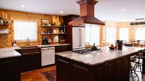 Una cocina moderna con paredes de madera, una isla central, una estufa y un ventanal grande.