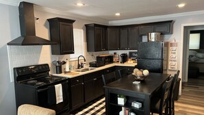 A modern kitchen with black cabinets, a black stove, and a black dining table.