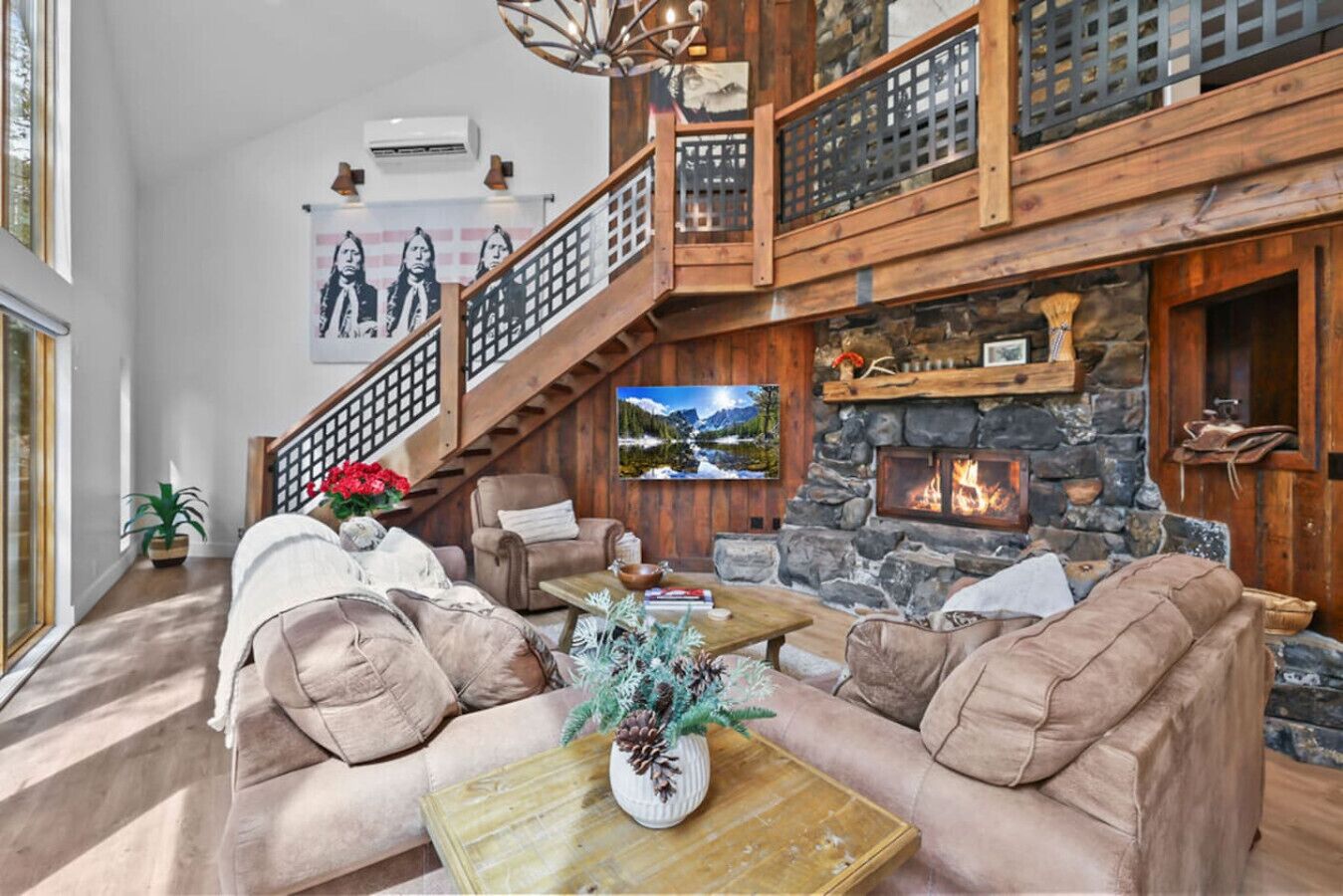 A spacious living room with a fireplace, a staircase, and a large window.