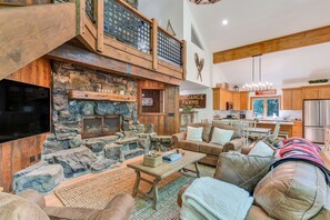 Cozy living area with a fireplace, kitchen, and high ceiling.
