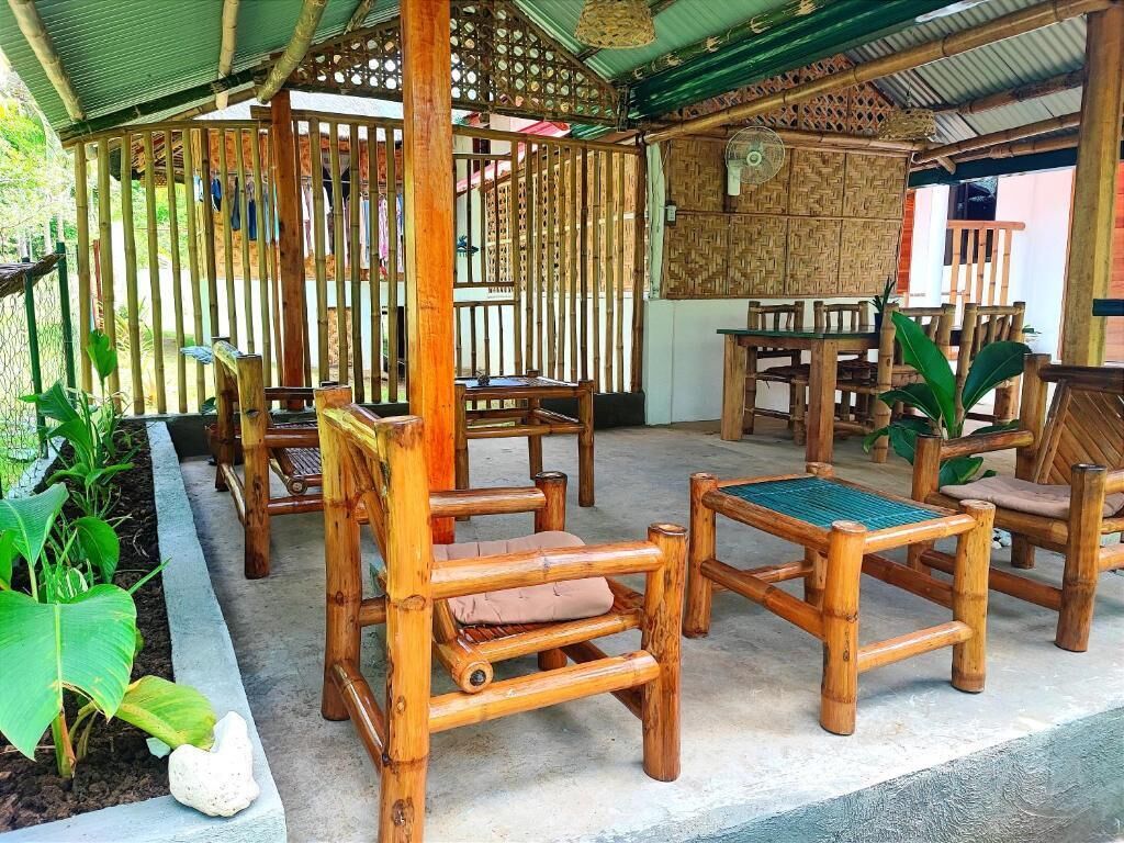 A bamboo-themed outdoor seating area with chairs and tables, surrounded by plants and a decorative fence.