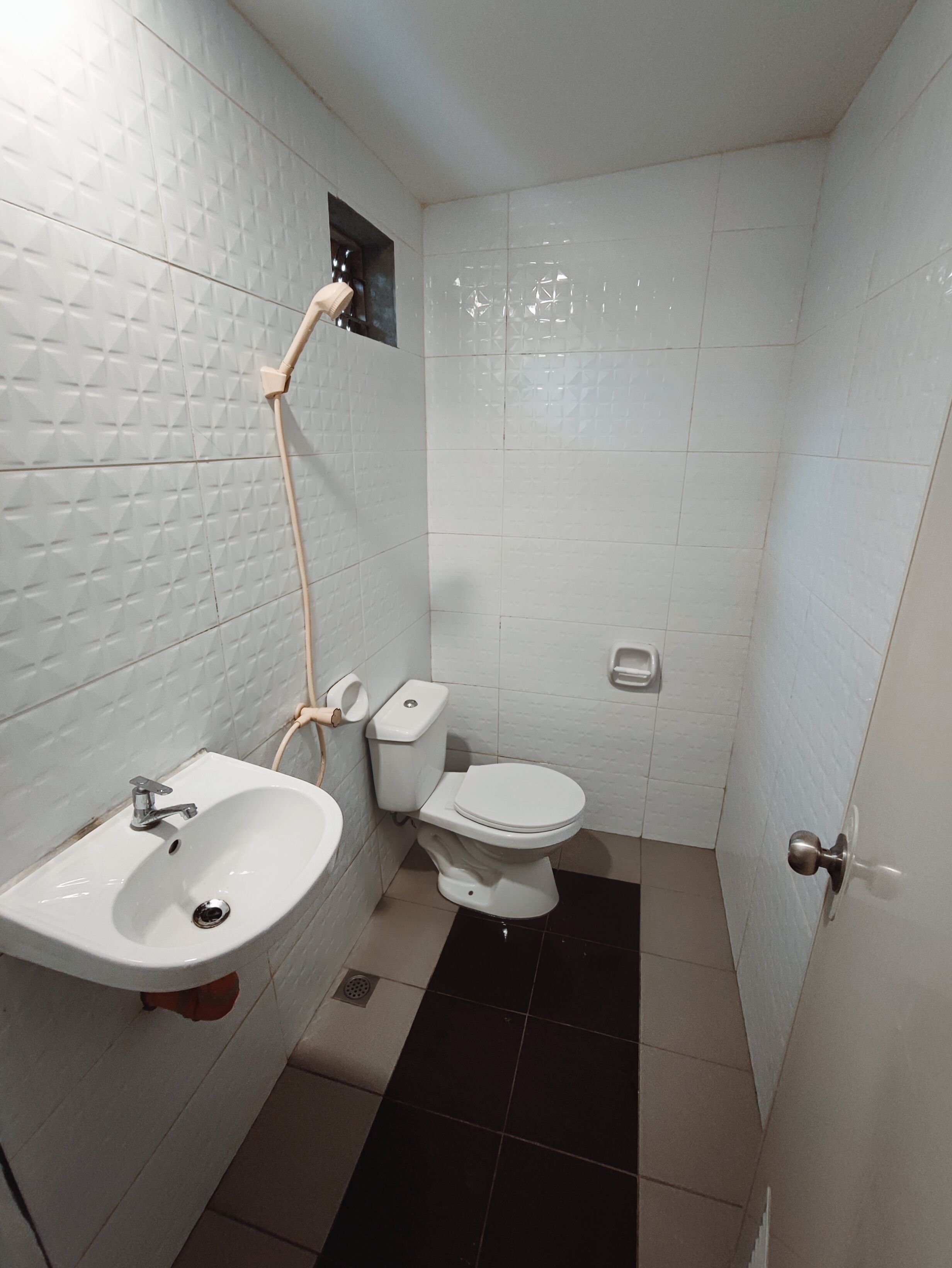 Un baño pequeño y limpio con lavamanos, inodoro y ducha blancos.