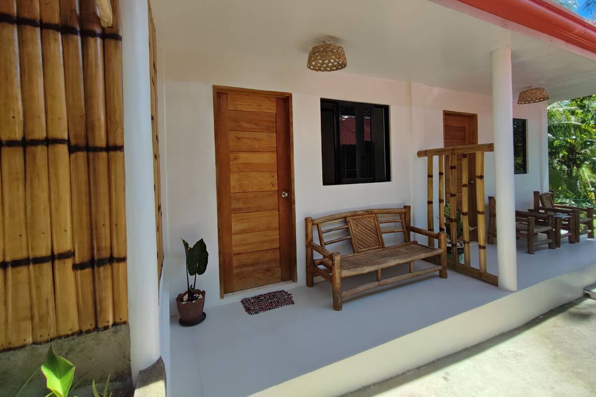 A covered porch with a wooden bench, a potted plant, and a wooden staircase.