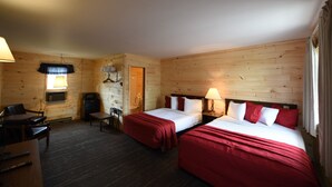 Una habitación de cabaña de madera con dos camas, un escritorio y una silla.