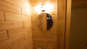 Un baño con paneles de madera, un lavabo, un espejo y una lámpara.