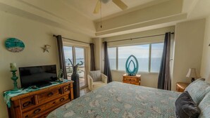 Un dormitorio con cama, cómoda, televisor, ventana con vistas y ventilador de techo.