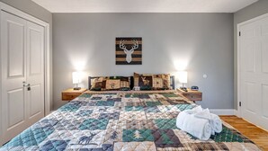 Une chambre à coucher comprenant un lit, deux tables de chevet, une lampe fixée au mur et un ventilateur de plafond.
