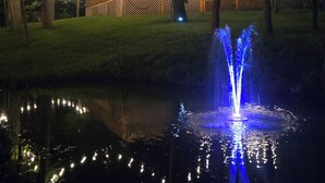 A nighttime outdoor scene with a fountain, string lights, and a wooden fence. - Fully renovated private & cozy 3 bdr cottage with hot tub close to Warren Dunes  (Sawyer)