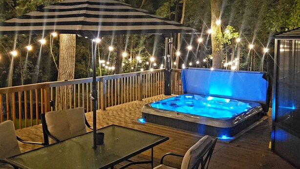 An outdoor deck with a hot tub, string lights, and seating. - Fully renovated private & cozy 3 bdr cottage with hot tub close to Warren Dunes  (Sawyer)