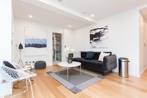 A modern living room with a sofa, coffee table, and a chair. - Spacious One Bedroom in Newmarket (Auckland)