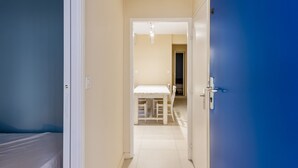 A hallway leading to a room with a bed and a dining area.