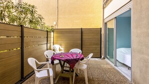 A small outdoor patio with a table and four chairs, surrounded by a wooden fence and a building wall.