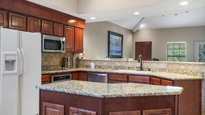 A kitchen with wooden cabinets, granite countertops, stainless steel appliances, and a large island. - Family-Friendly 3BR Retreat • Golf Course Views + Ticket Discounts (Branson)