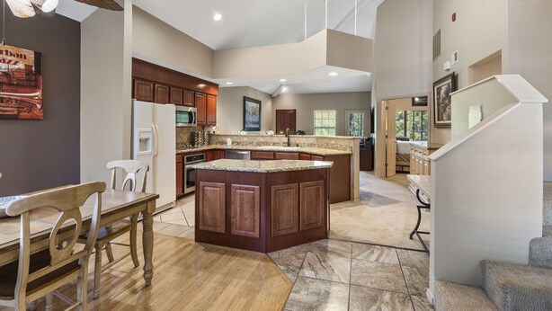 A spacious kitchen with a large island, wooden cabinets, and a dining area with chairs. - Family-Friendly 3BR Retreat • Golf Course Views + Ticket Discounts (Branson)