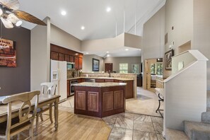 A spacious kitchen with a large island, wooden cabinets, and a dining area with chairs.