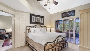 A bedroom with a large bed, a ceiling fan, a door leading to another room, and a view of the outdoors through a sliding glass door. - Family-Friendly 3BR Retreat • Golf Course Views + Ticket Discounts (Branson)