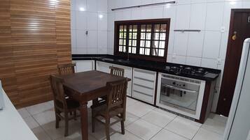 A kitchen with a wooden table and chairs, a window with a grid pattern, white cabinets, and a built-in oven.