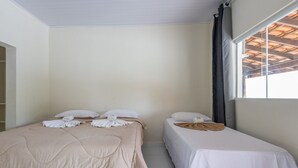 A room with two beds, each with white linens and pillows, and a window with a view of a wooden structure. - Maresias Suítes (São Sebastião)
