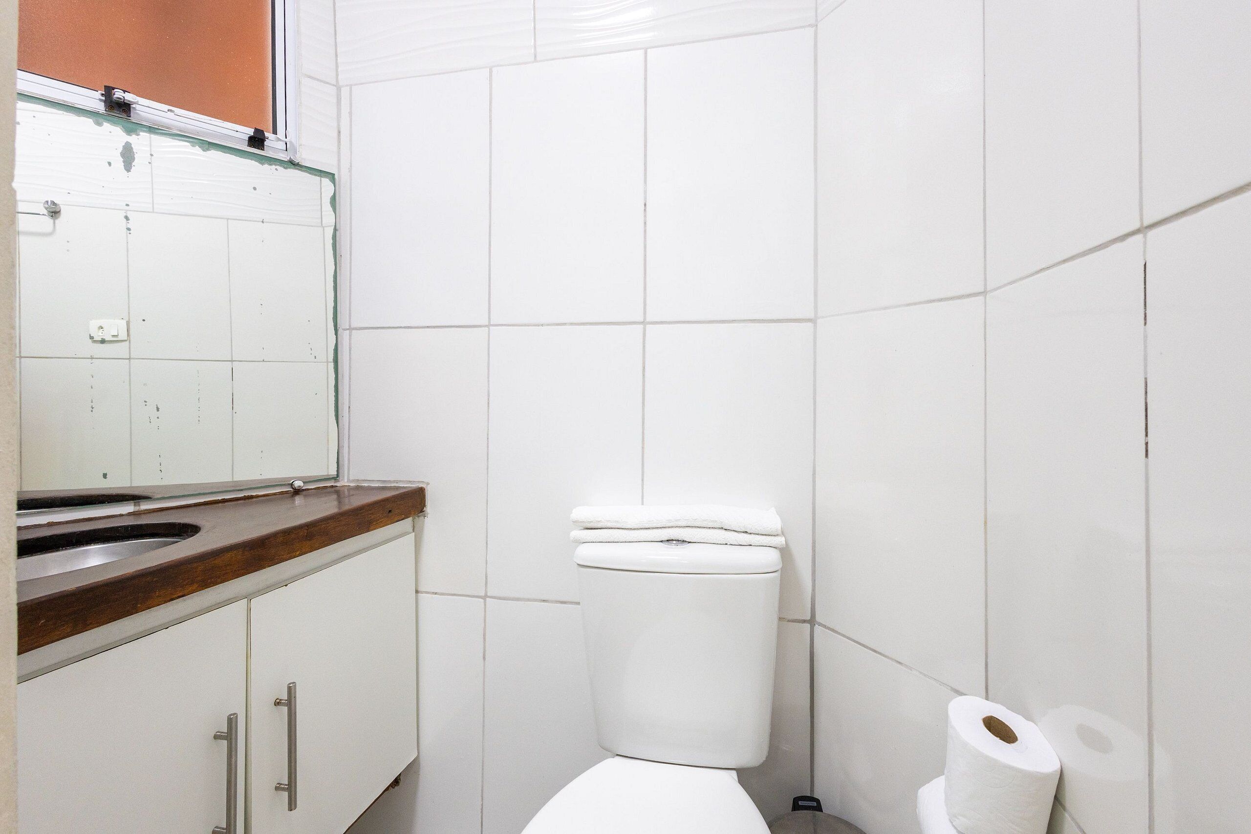 Een badkamer met toilet, wastafel en spiegel.