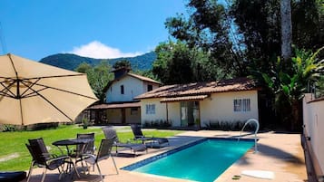 Una piscina al aire libre, sillones reclinables de piscina