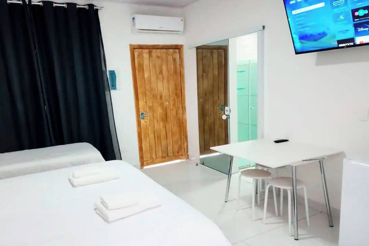 A hotel room with two beds, a desk, a chair, and a TV on the wall.