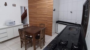 A compact kitchen with a wooden dining table, white cabinets, and a black stove. - Maresias Suítes (São Sebastião)