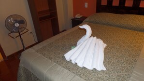 A hotel room with a bed, a standing fan, a telephone, and a small table. - HOSTAL ATACAMA (Tacna)