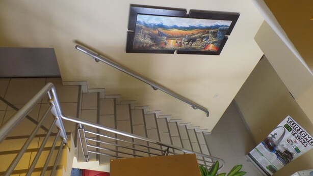 A staircase with metal railings, a wall-mounted television, and a poster advertising tourism in Tacna. - HOSTAL ATACAMA (Tacna)