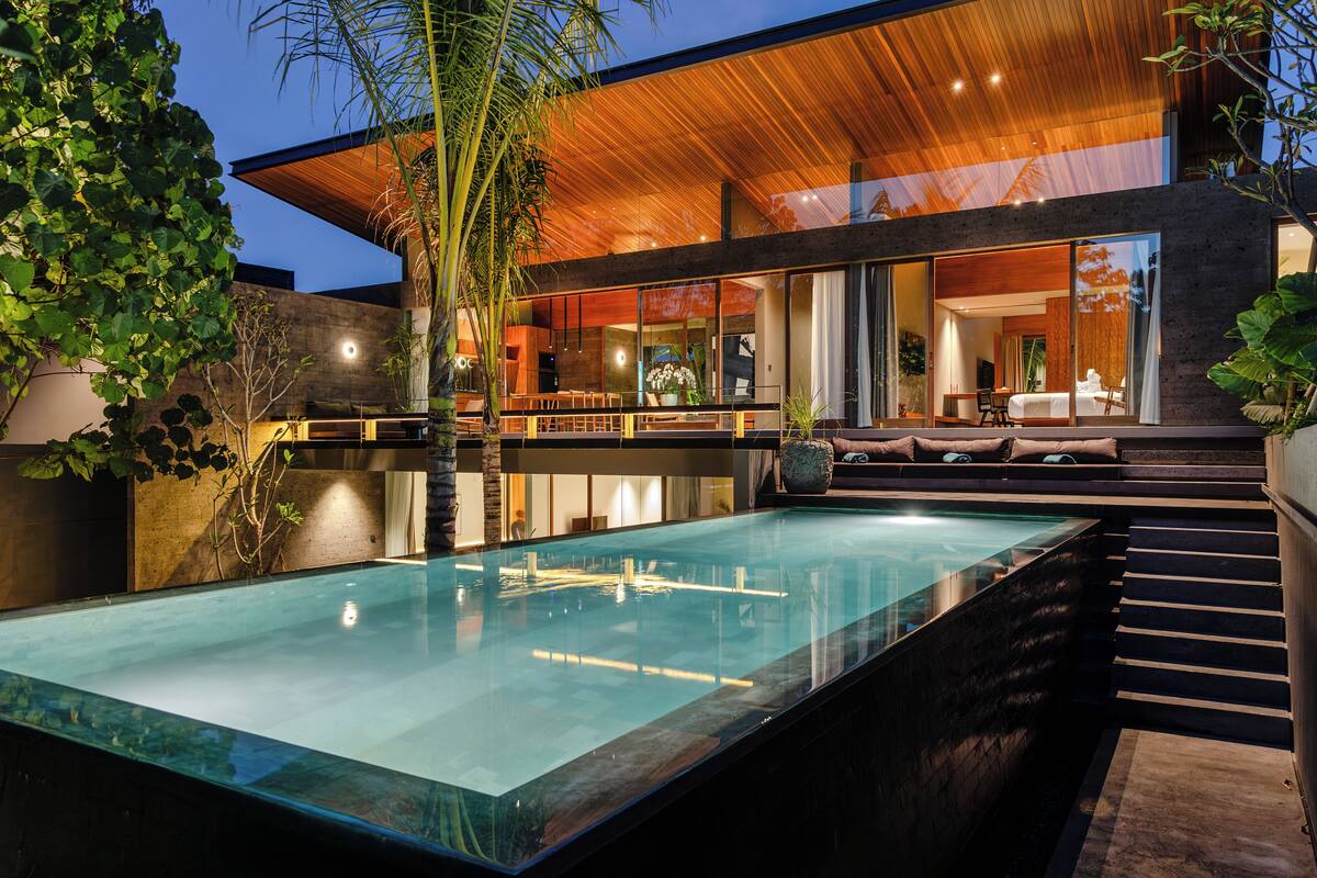 A modern house with a swimming pool, large windows, and a wooden ceiling.