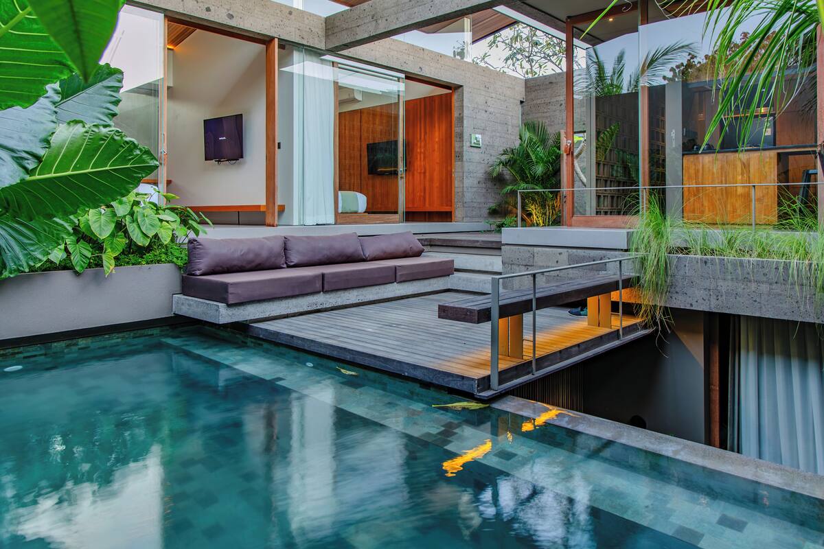 A modern outdoor living area with a pool, a wooden deck, and a built-in sofa.