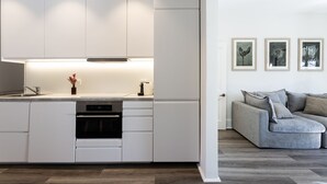 Une cuisine moderne avec des meubles blancs, un four encastré et un plan de travail agrémenté d’un vase de fleurs.