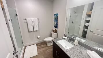 A modern bathroom with a shower, toilet, and sink.