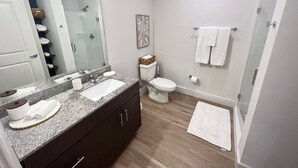 Ein modernes Badezimmer mit einem Granit-Waschtisch, einer Toilette und einer Duschkabine.