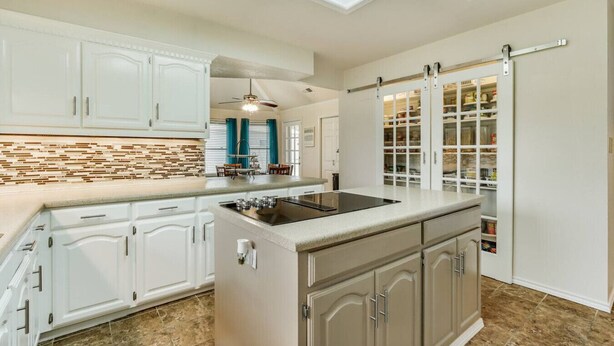 A kitchen with white cabinets, a built-in stove, and a pantry with glass doors. - Lake house with Hot tub 4 Bedroom and 3 Bath (Rowlett)