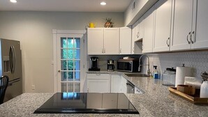 A modern kitchen with white cabinets, a granite countertop, and a built-in stove.
