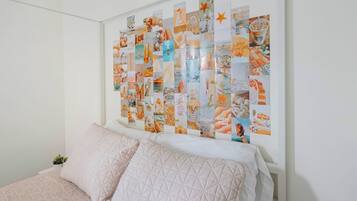 A bedroom with a bed, pillows, and a wall collage.