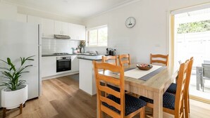 Een moderne keuken met witte kasten, een centraal eiland, houten stoelen en een eettafel.