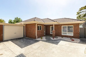 A two-story house with a brick exterior, a garage, and a covered patio area. - Family Beach Getaway (Rosebud)