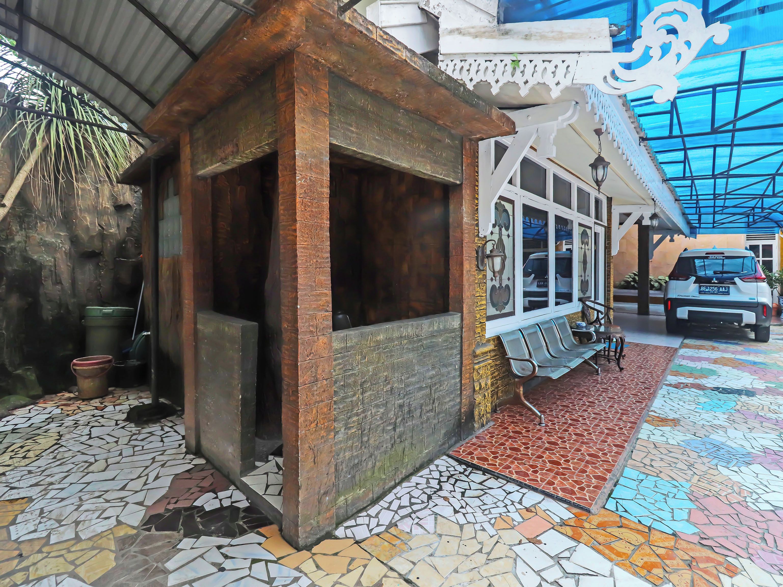 A building with a tiled floor, a covered entrance, and a parked car.