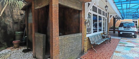 A building with a tiled floor, a covered entrance, and a parked car.