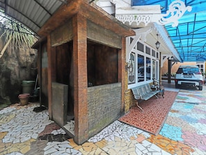 Un bâtiment à l’architecture rustique, avec une structure en bois, un sol carrelé et une voiture garée à l’extérieur.